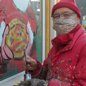 Jean-Marie Lesage terminant au pinceau le noir de la décoration sur une vitrine. Photo de Sandra Deruère, photographe pour le site de la ville d'Arcueil (Paris)